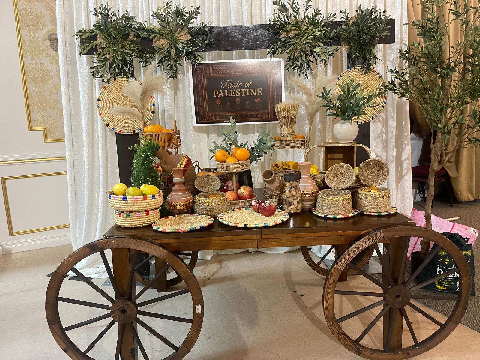 Taste of Palestine cultural art installation with traditional wooden cart, olive branches, and handcrafted cultural artifacts